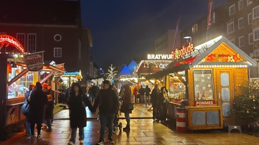 Mehrere Menschen schlendern über den Bremerhavener Weihnachtsmarkt.