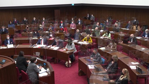 Die Bremische Bürgerschaft während einer Sitzung. Die Abgeordnete sitzen durch Plexiglasscheiben getrennt nebeneinander.