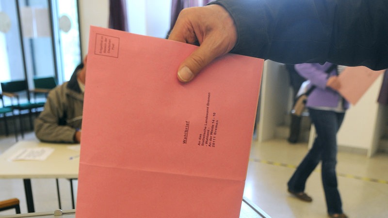Ein Briefwähler, der persönlich beim Wahlamt Bremen vorbeigekommen ist, wirft seinen Umschlag in die Urne