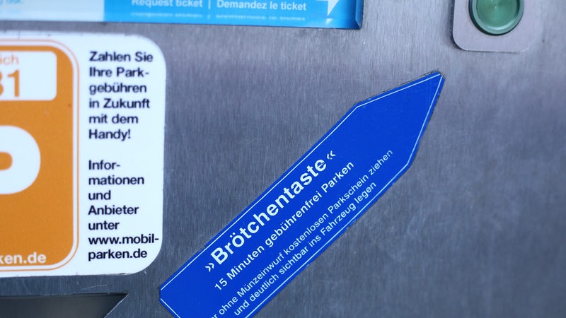 Ein Pfeil weist an einem Parkscheinautomaten auf die sogenannte "Brötchentaste" hin.