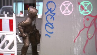 Eine Bronzefigur, die von einem Unbekannten in Hamburg unter der U-Bahn-Haltestelle Rödingsmarkt platziert wurde.