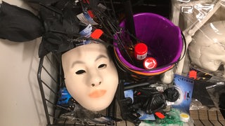 In einem Regal liegen eine Maske aus Plastik und andere Gegenstände.