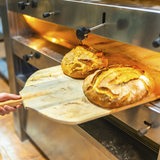 Ein Bäcker holt frisches Brot aus dem Ofen