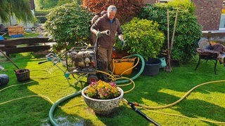 Ein Mann beim Aufbau eines Brunnens in seinem Garten