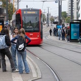 Fahrgäste stehen an der Haltestelle Domsheide in Bremen während eine Bahn einfährt.