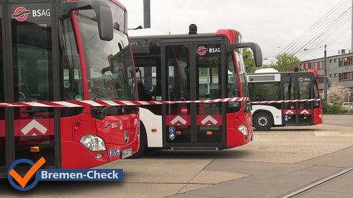 Drei Busse der BSAG sind auf einem Parkplatz, hinter einem Absperrband zu sehen.