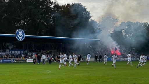 Der Bremer SV beim Spiel, im Hintergrund Pyrotechnik