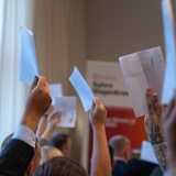 Mehrere Hände halten Stimmkarten in die Luft