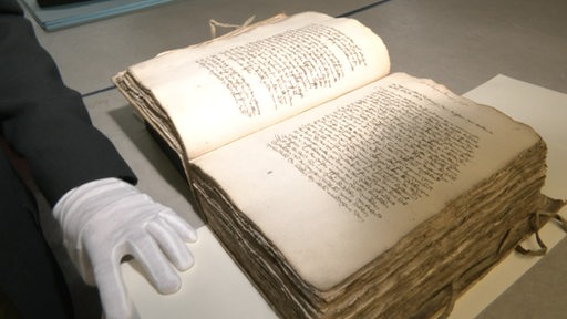 Ein Buch liegt auf einem Tisch, in welchem die Handschrift des Bremer Rates zu sehen ist.