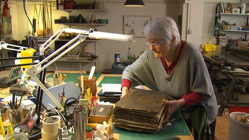Birgit Drücker in ihrer Buchbinderwerkstatt mit Bücher und Materialien.