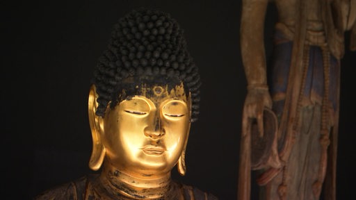 Eine Figur des Buddha wird von einem Scheinwerfer angestrahlt. 