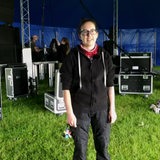 Eine Frau in Arbeitskleidung steht vor einer Bühne.