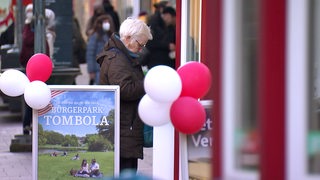 Eine Dame kauft sich eine Lose am Bürgerpark Tombola Stand in Bremen.