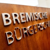 Ein Schriftzug hängt an einem Rednerpult im Plenarsaal der Bremischen Bürgerschaft. 