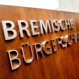 Auf einem Holzpult steht der Schriftzug "Bremische Bürgerschaft".