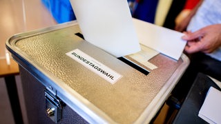 Ein Wähler wirft in einem Wahllokal, das im Klassenraum einer Grundschule im Stadtteil Prenzlauer Berg untergebracht ist, seinen Stimmzettel für die Bundestagswahl in eine Wahlurne.