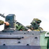 Ein Soldat schaut oben aus der Öffnung eines Panzers, an der linken Seite des Bildes ist eine Hand zu sehen.
