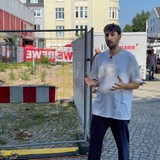 Max steht auf einem Platz in der Bremer Neustadt vor einem Bauzaun.