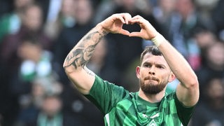 Oliver Burke formt mit seinen Händen ein Herz.