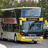 Ein gelb-weißer Bus mit der Aufschrift "Der Hafenbus" fährt eine Straße entlang.