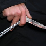 Ein Jugendlicher hält ein Butterfly-Messer in der Hand.