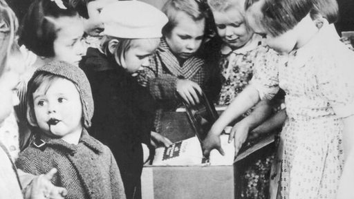 Archivbild: Zahlreiche Kinder packen eine Care-Paket aus.