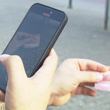 Ein Mann hält in einer Hand ein Handy, in der anderen einen 10-Euro-Schein.