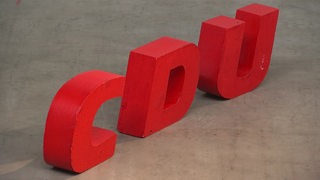 Das Logo der CDU in roten Buchstaben, die auf dem Boden stehen.