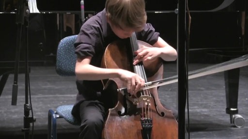 Ein junger Mann spielt das Cello.
