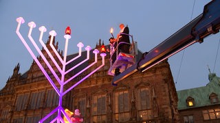 Bürgermeister Bovenschulte und Rabbiner Shmuel Havlin vor einem Kerzenleuchter.