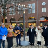 Mehrere Personen stehen unter einem großen Kerzenständer.