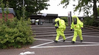 Feuerwehrleute kleiden Kollegen mit Schutzausrüstung und Atemmasken ein