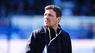 Werder Bremens Geschäftsführer Clemens Fritz blickt nach rechts und ist leicht geblendet von der Sonne.
