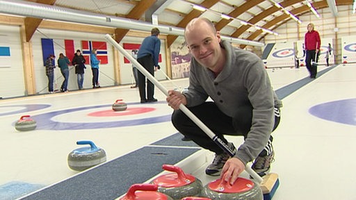 Reporter hockt neben Curling-Stein