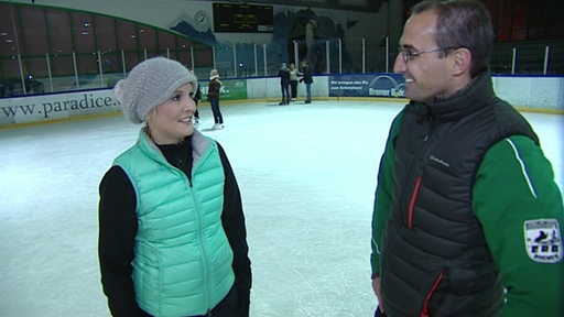 Reporterin und Trainer stehen in der Eishalle