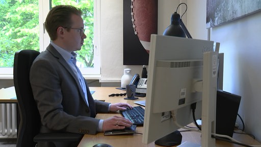 Ein Mann sitzt in einem Büro an einem Computer.