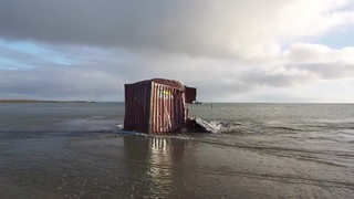 Ein zerstörter Container an einem Strand an der Nordsee