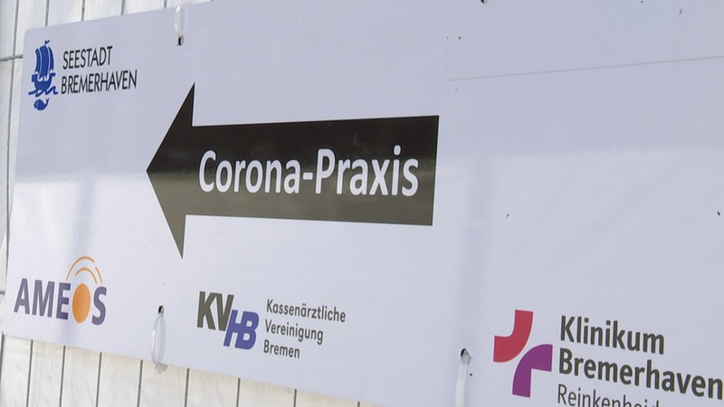 Ein Schild mit einem schwarzen Pfeil, mit der Aufschrift Corona Praxis.