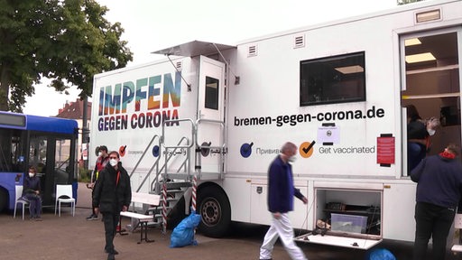 Ein Impfbus in Bremen, vor dem Menschen gehen.