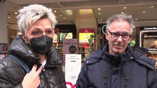 Eine Frau trägt eine Schutzmaske. Neben ihr ein Mann ohne Maske.