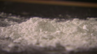 Eine weißliche, pulverförmige Substanz wird auf einem Tisch ausgekippt