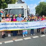 Mitglieder des Senats halten beim CSD ein Plakat hoch.