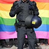 Ein Polizist steht vor einer Regenbogenfahne während eines Umzuges zum Christopher-Street-Day (CSD).