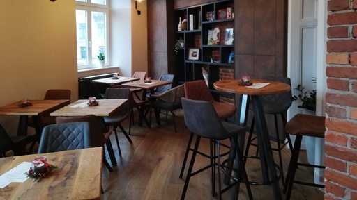 Im Café im Cuxhavener Wasserturm stehen mehrere Holztische und Holzstühle.