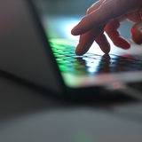 Eine Hand fährt über die Tastatur eines Laptops.