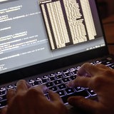  Quellcode eines Webservers sowie die Windows-Eingabeaufforderung sind einem Laptop im Dunkeln zu sehen.