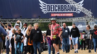 Besucher des Deichbrands schlendern über das Festival-Gelände.