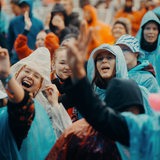 Mit Regenponchos ausgestattete Menschen feiern auf dem Deichbrand-Festival und trotzen dem schlechten Wetter.
