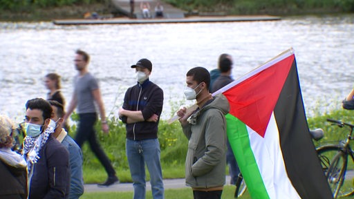 Eine Person mit Palästina-Flagge auf einer Demo.
