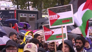 Menschen mit Regenschirmen stehen vor dem Bremer Hauptbahnhof.